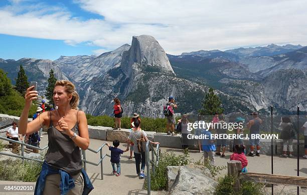 This August 5, 2015 photo shows a woman taking a selfie atop Glacier Point with a background view of Half Dome at Yosemite National Park. A second...