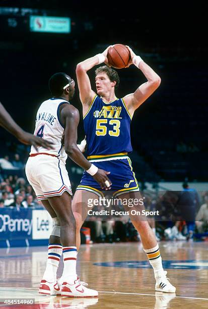 Mark Eaton of the Utah Jazz looks to pass the ball over the top of Moses Malone of the Washington Bullets during an NBA basketball game circa 1986 at...