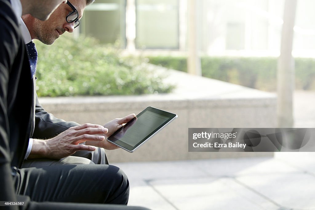 Two businessmen discussing plans on a tablet.