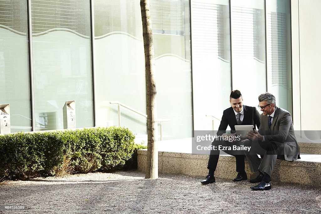 Two businessmen discussing plans on a tablet.