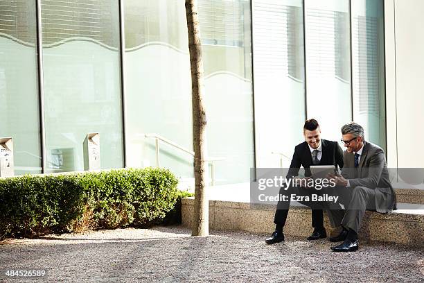 two businessmen discussing plans on a tablet. - buildings side by side stock pictures, royalty-free photos & images