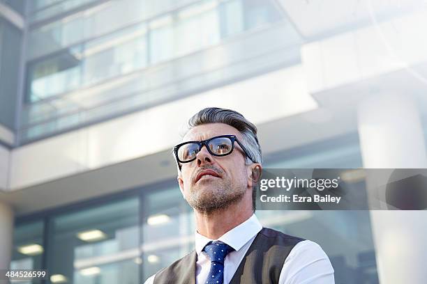 businessman looking up at a sky scraper. - one person looking up stock pictures, royalty-free photos & images
