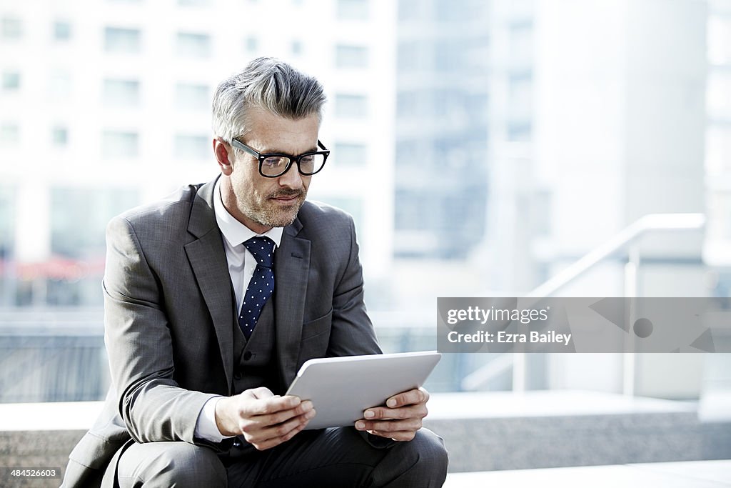 Businessman using a tablet outside in the city.