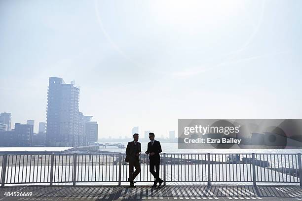 two businessmen silhouetted against city skyline. - corporate skyline stock pictures, royalty-free photos & images