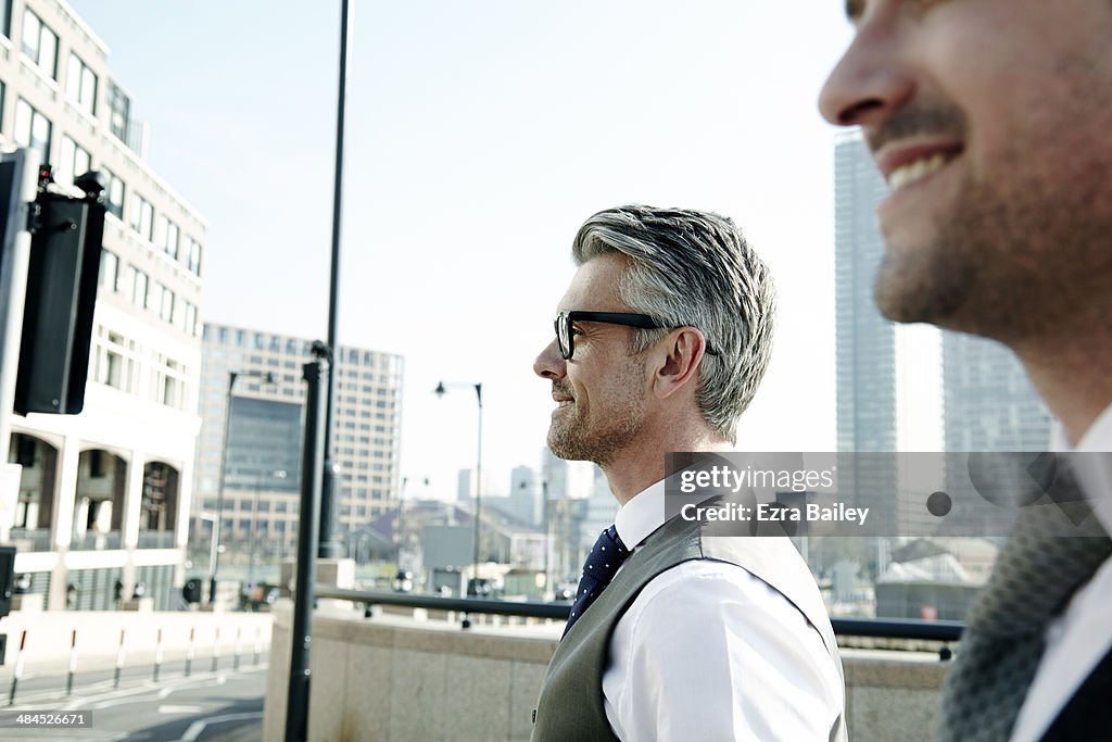 Two businessmen talking on the move, in the city.