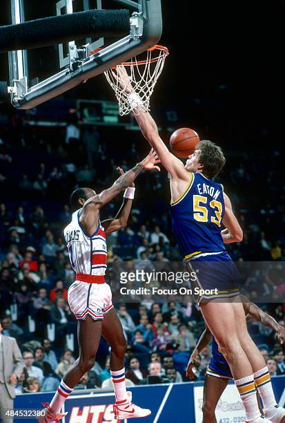 Mark Eaton of the Utah Jazz attempts to block the pass of Gus Williams of the Washington Bullets during an NBA basketball game circa 1985 at the...