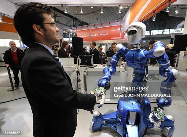 German robotics engineer Thomas Wimboeck shakes hands with the "mobile robotic system" Rollin' Justin at the world's biggest high-tech fair, the...