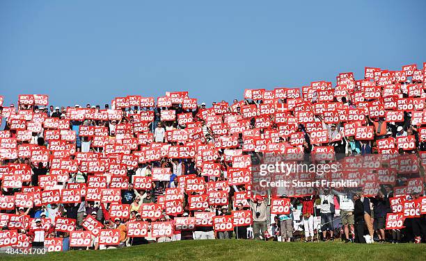 Soren Kjeldsen of Denmark walks onto the 16th green as fans hold placards to celebrate the 500th tournement during the first round of the Made in...