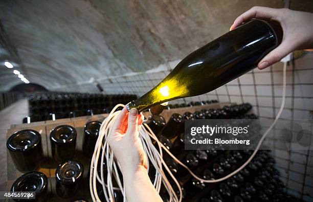 Degorger uses a light bulb to inspect sediment in a bottle of champagne at the Abrau-Durso PJSC Winery in Abrau Durso Village, Russia, on Tuesday,...