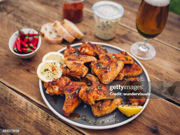 würzige chicken wings mit beilagen und einem glas bier - chicken wings stock-fotos und bilder