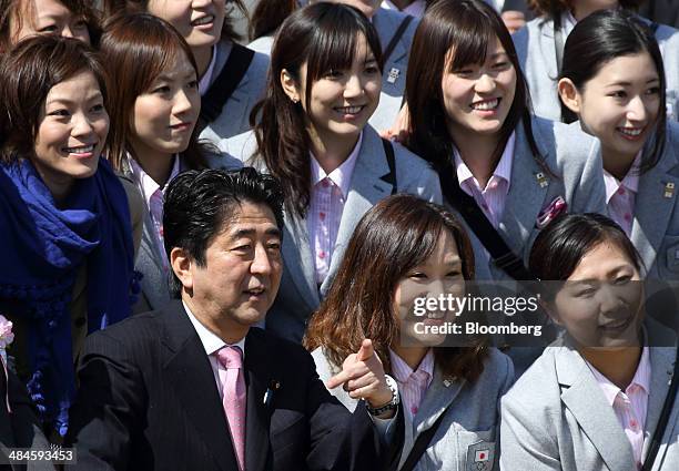 Shinzo Abe, Japan's prime minister, left in the front row, gestures as he poses for photographers with guest attendees from the Japanese Olympic team...