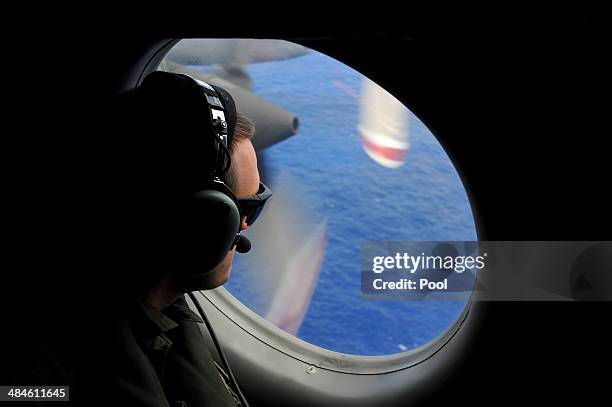 Crew member of a Royal New Zealand Airforce P-3K2-Orion aircraft helps to look for objects during the search for missing Malaysia Airlines flight...