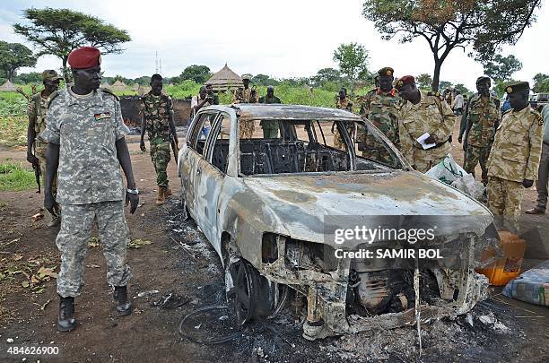 South Sudanese SPLA soldiers inspect a burned out car in Pageri in Eastern Equatoria state on August 20, 2015. The spokesman of SPLA, Colonel Philip...