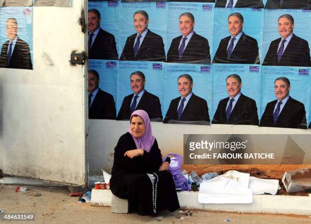 Woman sits in front of electoral posters of independent candidate to Algeria's presidential election Ali Benflis, on the last day of the electoral...