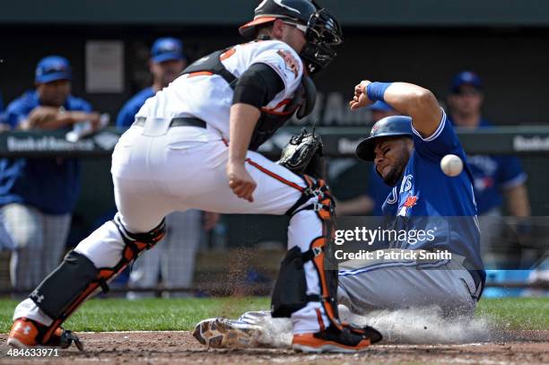 Melky Cabrera of the Toronto Blue Jays slides safe into home plate in front of catcher Matt Wieters of the Baltimore Orioles as he scores off of a...
