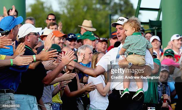 Bubba Watson of the United States holds his son Caleb on the 18th green after winning the 2014 Masters Tournament by a three-stroke margin at Augusta...