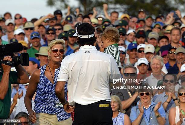 Bubba Watson of the US carries his son Caleb as walks to his wife Angie after putting on the 18th green during the 78th Masters Golf Tournament at...