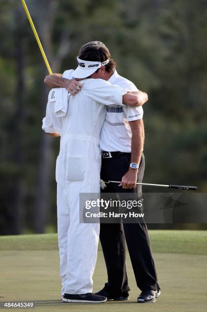 Bubba Watson of the United States celebrates with his caddie Ted Scott on the 18th green after winning the 2014 Masters Tournament by a three-stroke...