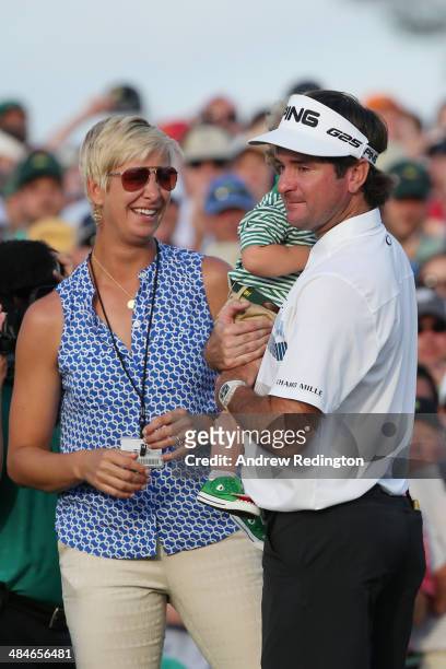 Bubba Watson of the United States waits with his wife Angie and their son Caleb on the 18th green after winning the 2014 Masters Tournament by a...