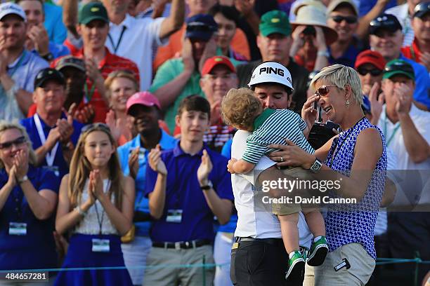 Bubba Watson of the United States celebrates with his wife Angie and their son Caleb on the 18th green after winning the 2014 Masters Tournament by a...