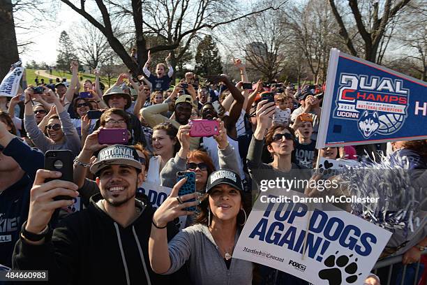 People line the sidewalk and cheer as the University of Connecticut's men's and women's basketball teams pass by during a victory parade to celebrate...