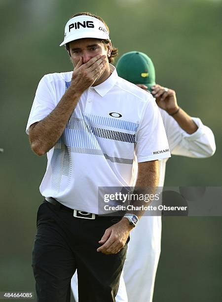 Bubba Watson covers his mouth as his son, Caleb Watson, walks onto the green following Watson's final putt to win The Masters at Augusta National...