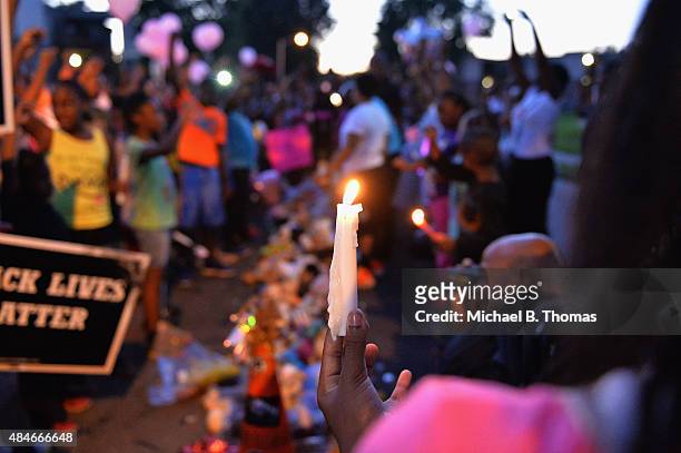 Girl holds a candle as children gather at the Michael Brown Jr. Memorial on Canfield Drive during a candlelight vigil held in honor of Jamyla Bolden...