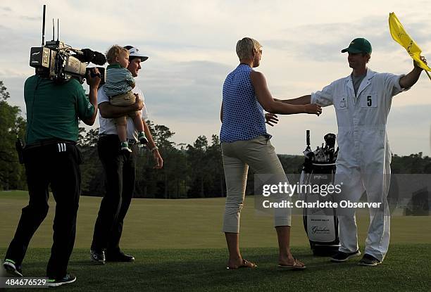 Bubba Watson holds his son, Caleb as his wife, Angie, hugs caddie, Ted Scott, following The Masters at Augusta National Golf Club in Augusta, Ga.,...