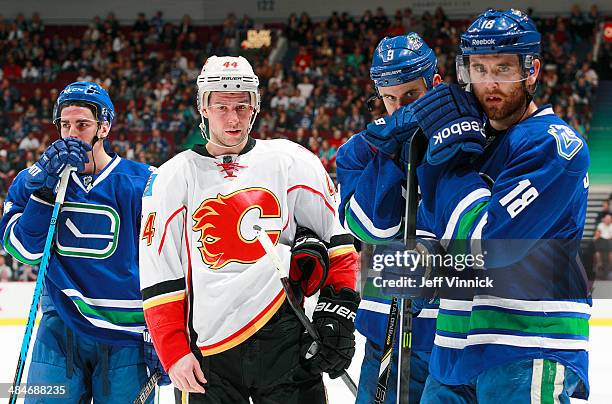 Chris Butler of the Calgary Flames, Alexandre Burrows, Zack Kassian and Ryan Stanton of the Vancouver Canucks watch with concern as Daniel Sedin of...