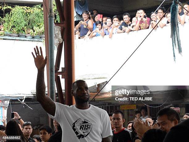 Superstar LeBron James of the US gestures as he visits a government mass housing project as part of the clinic session in Manila on August 21, 2015....