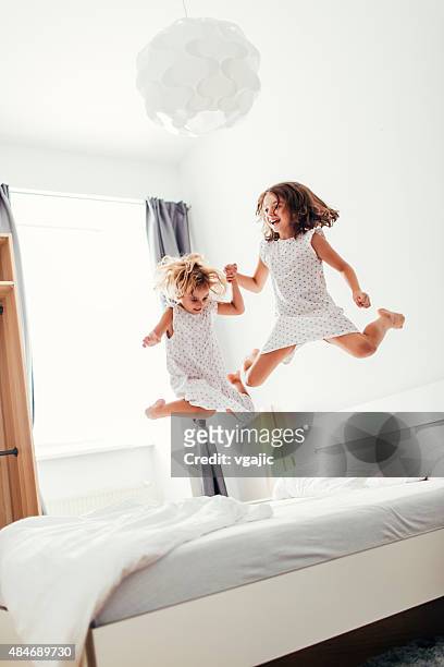 geschwister springen auf dem bett. - children jumping bed stock-fotos und bilder