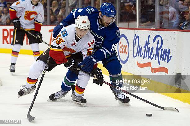 Ryan Stanton of the Vancouver Canucks and Johnny Gaudreau of the Calgary Flames battle for the puck during the third period in NHL action on April...