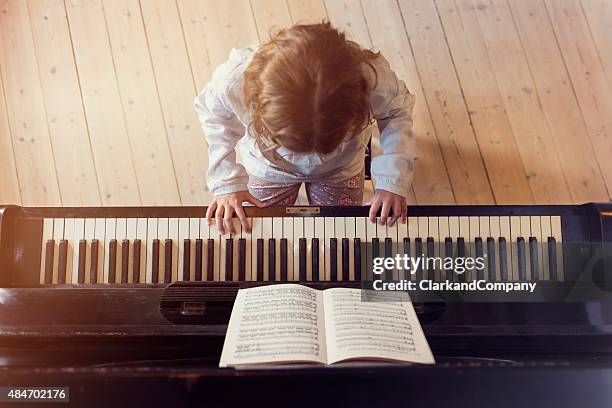 overhead view of young girl playing piano in sunlight room - pianist stockfoto's en -beelden