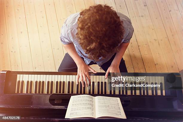 overhead view of teenage boy playing piano in sunlight room - keyboard white stockfoto's en -beelden