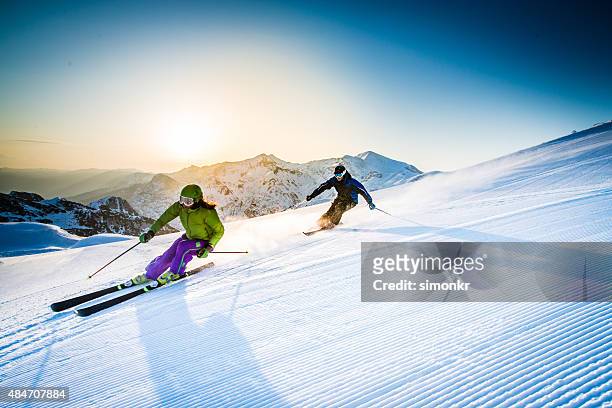 mann und frau skifahren alpin - skifahren und snowboarden stock-fotos und bilder
