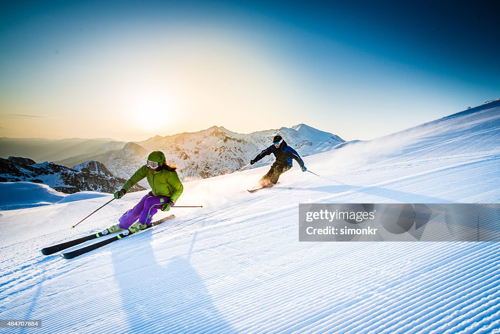 Man and woman skiing downhill