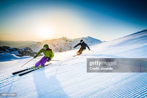 man and woman skiing downhill - skiing and snowboarding stock pictures, royalty-free photos & images