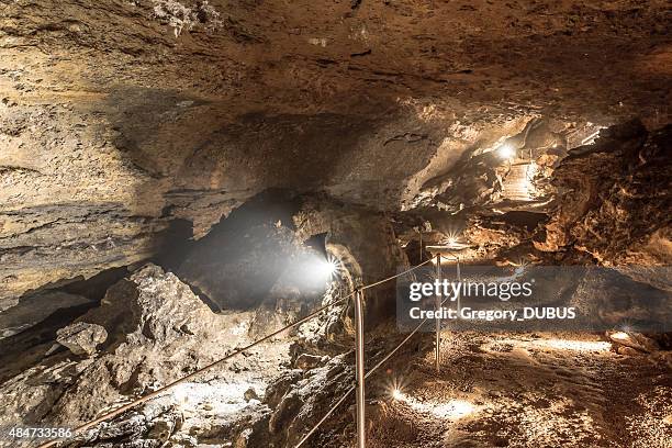 illuminated footpath with railing to visit caves of la balme - 洞窟 個照片及圖片檔