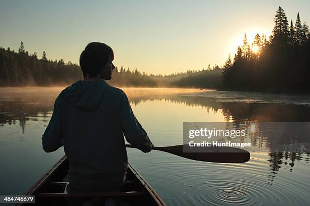 joven una canoa con balancines en puesta de sol - proa fotografías e imágenes de stock