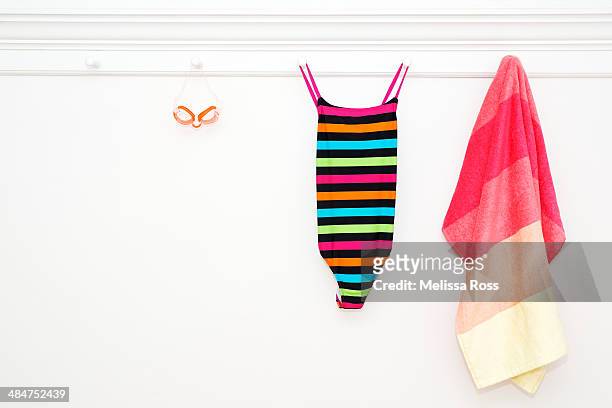 swimsuit, goggles and beach towel hung from pegs - swim suit stock pictures, royalty-free photos & images