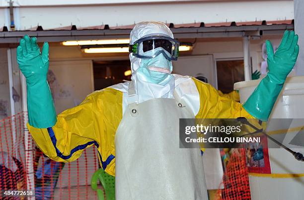 Health worker wearing protective gear is sprayed with disinfectant at the Nongo ebola treatment centre in Conakry, Guinea, on August 21, 2015. The...