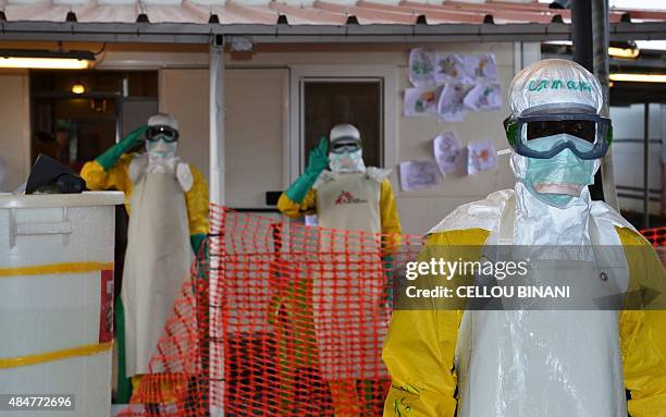 Health workers wearing protective gear gesture at the Nongo ebola treatment centre in Conakry, Guinea, on August 21, 2015. The World Health...