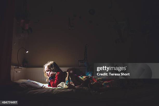 girl reading in her bed at night - child reading a book stockfoto's en -beelden