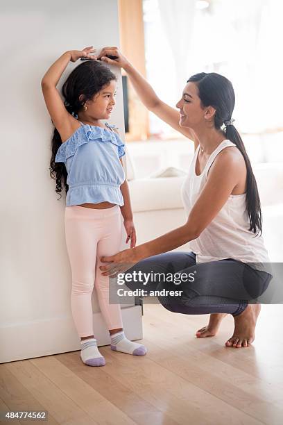 mother checking daughters height - child height measure stock pictures, royalty-free photos & images