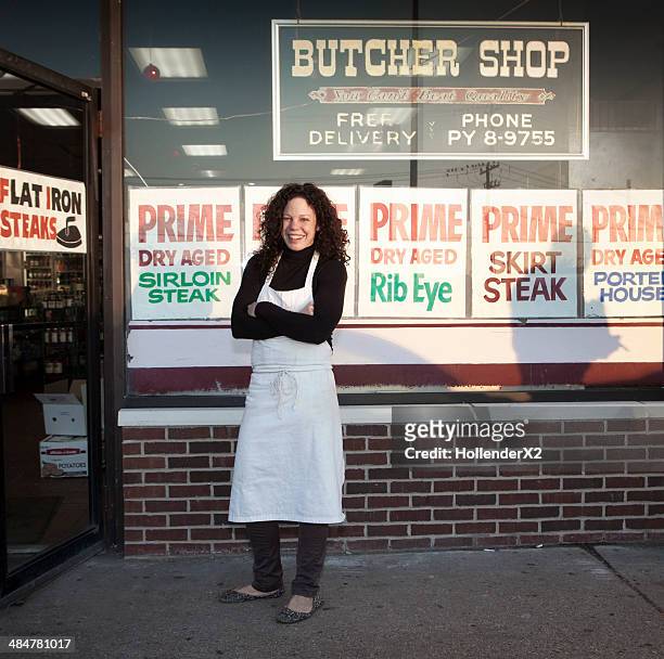 woman butcher standing in front of butcher shop - metzgerin stock-fotos und bilder