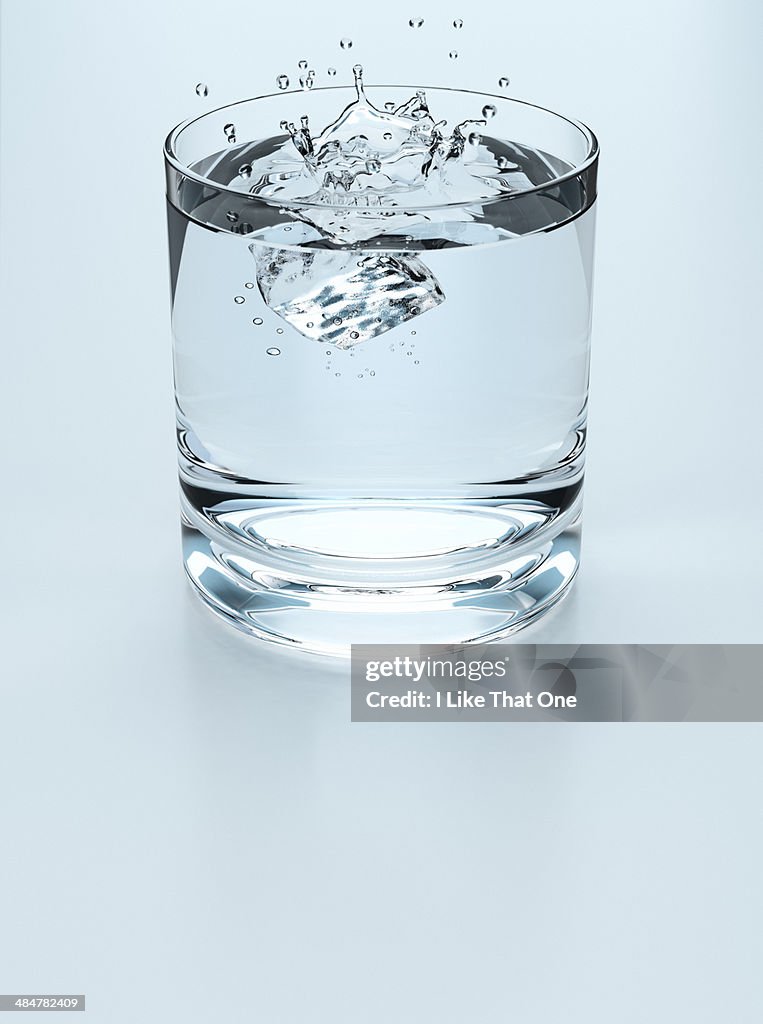 Ice cube falling into a drinking glass of water