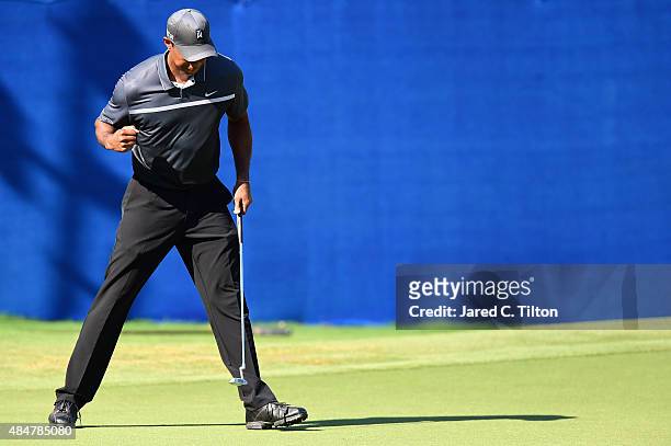 Tiger Woods reacts after making an eagle putt on the 15th green during the second round of the Wyndham Championship at Sedgefield Country Club on...