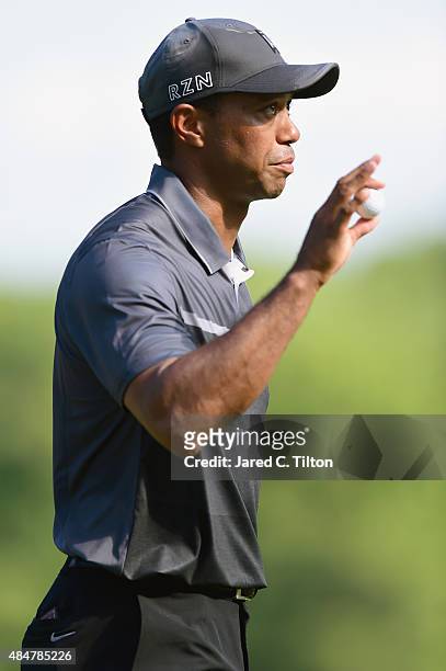 Tiger Woods waves to the crowd after making a par putt on the 17th green during the second round of the Wyndham Championship at Sedgefield Country...