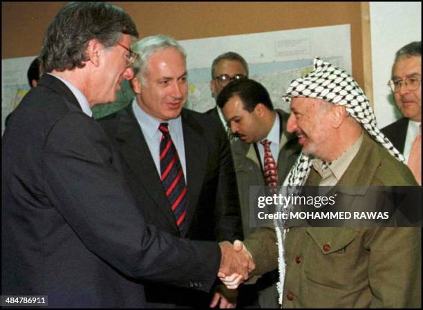 Palestinian Authority President Yasser Arafat shakes hands with US envoy Dennis Ross, as Israeli Prime Minister Benjamin Netanyahu looks at the Erez...