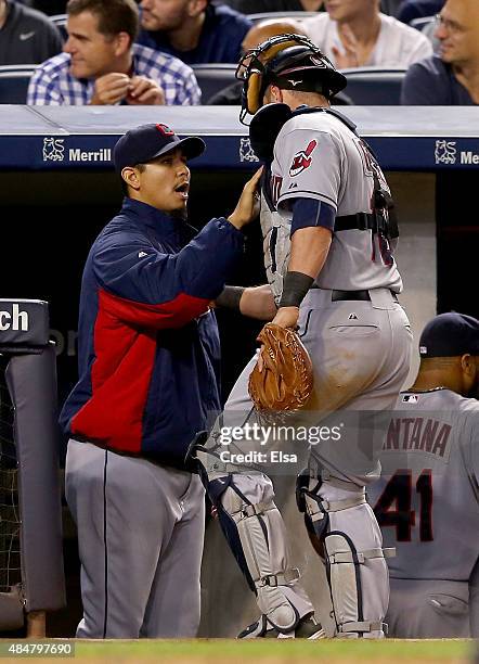 Carlos Carrasco of the Cleveland Indians congratulates teammate Yan Gomes after Gomes heads for the dugout in the seventh inning against the New York...